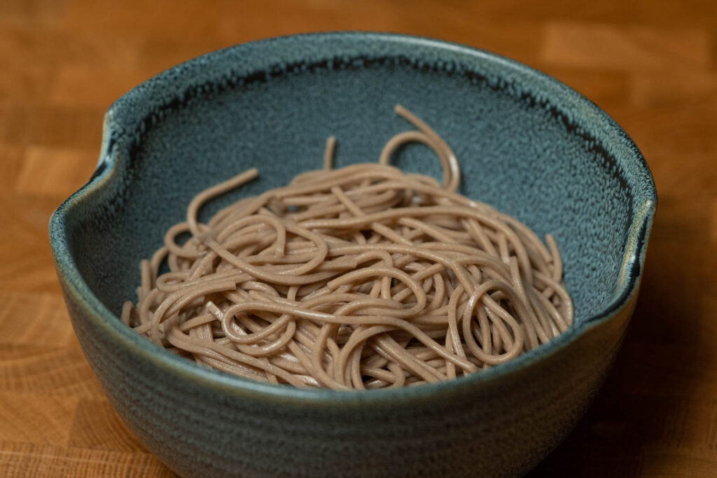 Assemble dish with soba noodles at the bottom